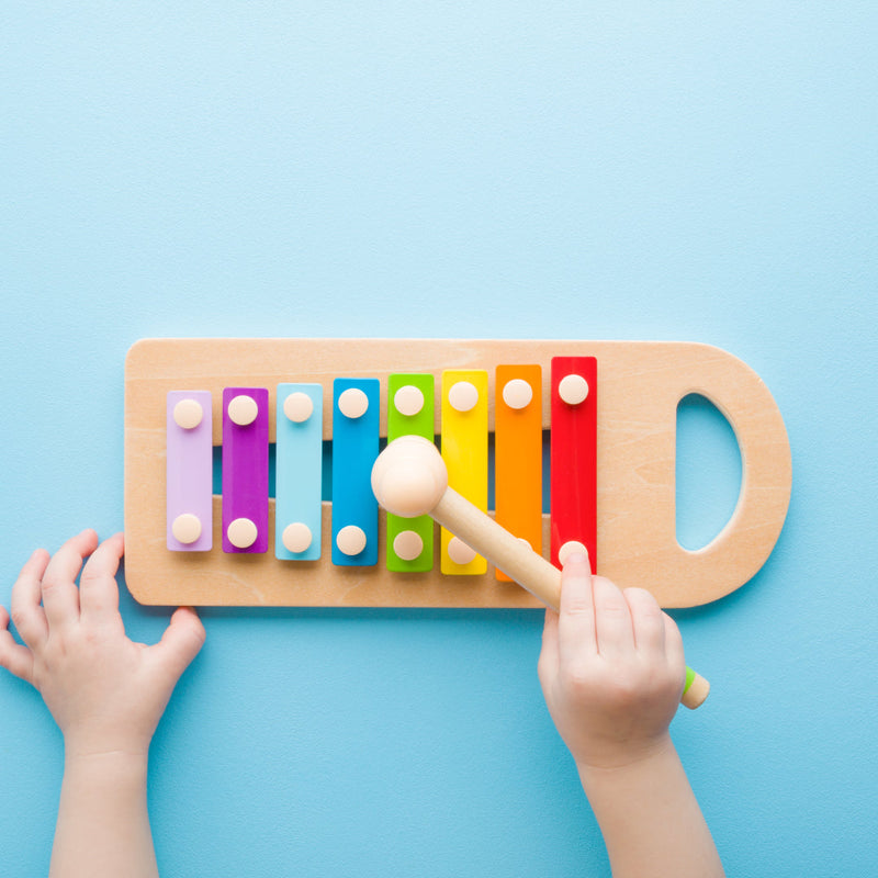A child's hands playing a xylophone