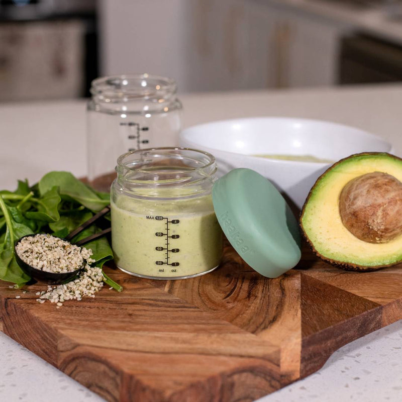 Green Kiwifruit Puree baby food in Haakaa glass jar with half nan avocado, oats and spinach.
