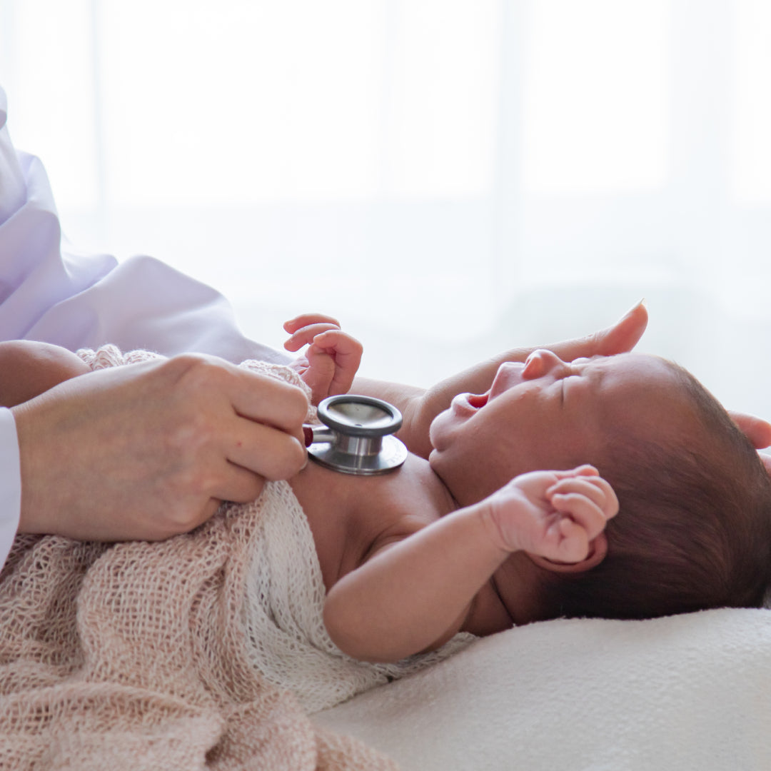 Doctor checking crying baby's chest with a stethoscope