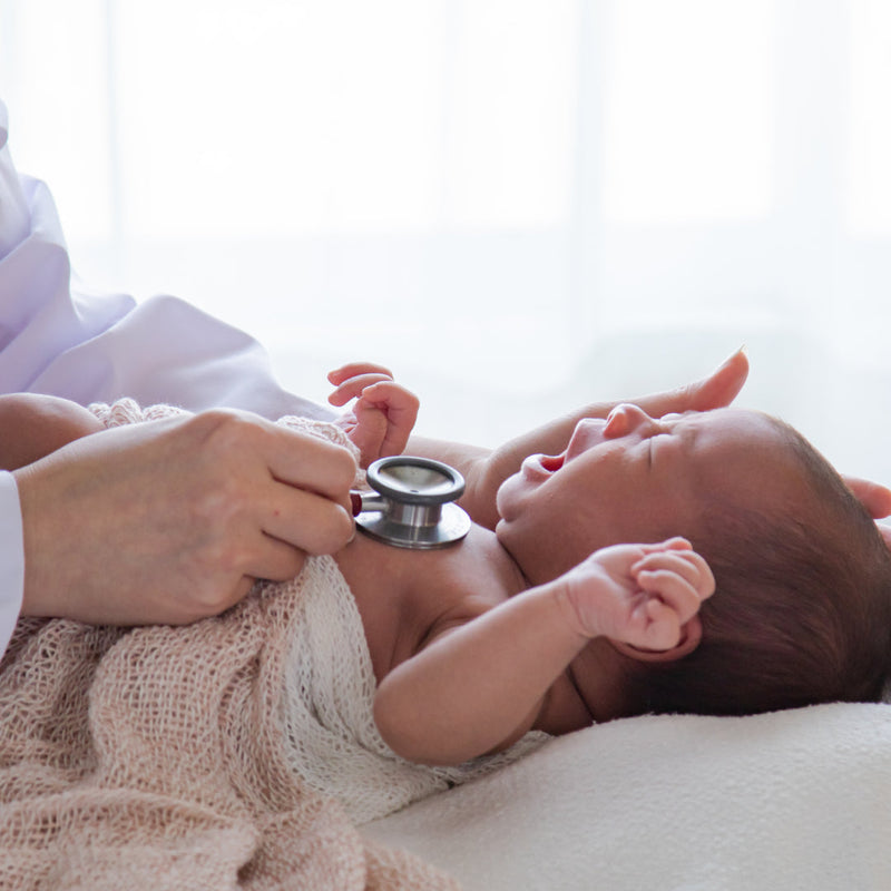 Doctor checking crying baby's chest with a stethoscope