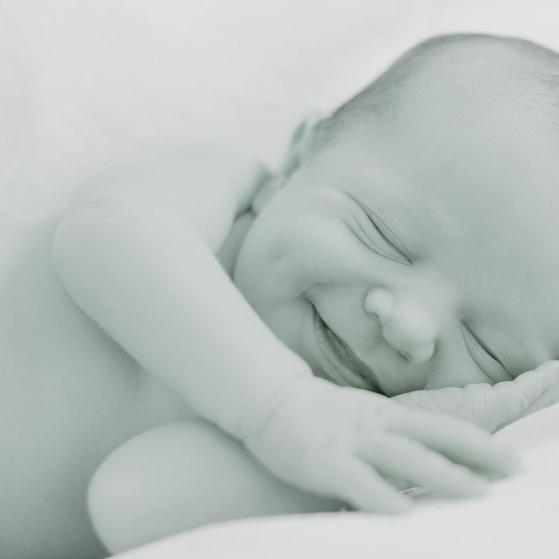 Black & White photo of a baby sleeping with a big smile